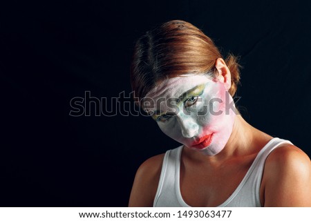 Young woman applying make-up, paints face with painting brush and makeup. How not to do make up concept.