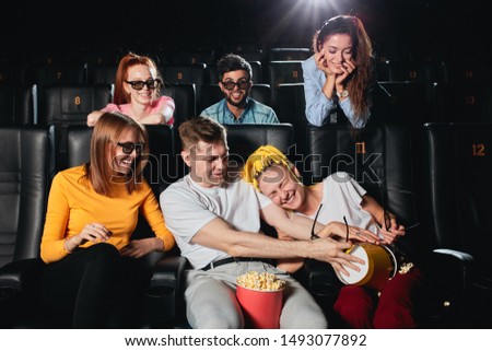 Attractive young couple having fun with popcorn while other people watching them. close up photo