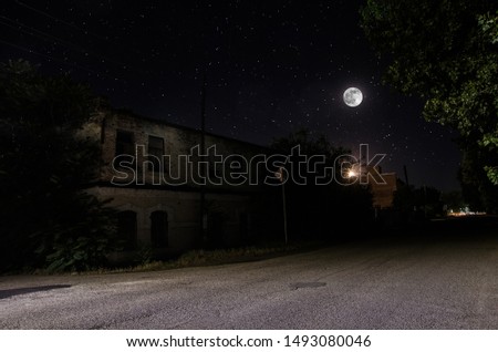 Full moon over quite village at night. Beautiful night landscape of old town street with lights