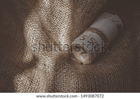 Cash debt recovery. Banknotes twisted and tied with twine on burlap. Soft background. Close-up. Horizontal photo layout
