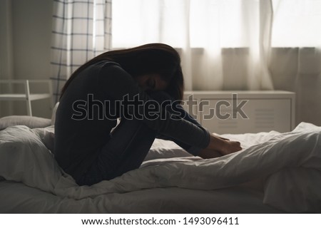 Suffer from depression , mental health problem. asian young woman sitting on the bed feeling depressed. Royalty-Free Stock Photo #1493096411