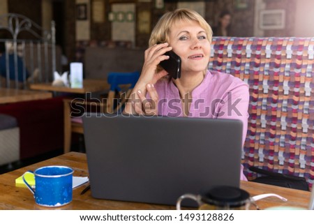 Businesswoman is sitting at table in front of laptop . Education for adults. Pensioner freelancer works. Woman is chatting, blogging, checking email. Social media, network.