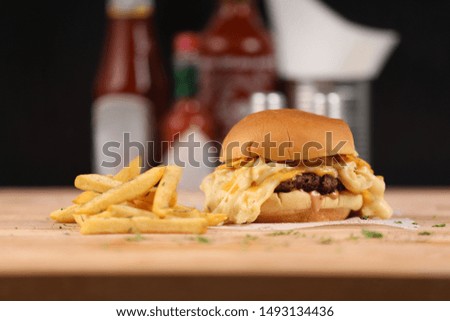 neat burger with chess and ketchup and fries on wood background
