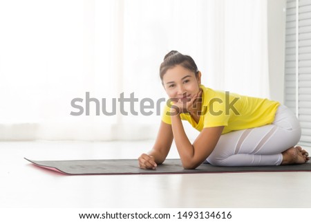 young Asian lady wearing yellow t shirt doing exercise Yoga pose in the bedroom in the morning after woke up.