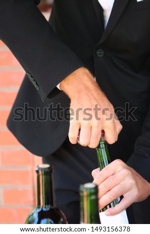 A sommelier man opens a bottle of wine with a corkscrew. Photo without a face. Hands close up. Wine tasting concept.Party or celebration in a big company.