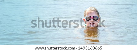 blonde girl, in glasses for snorkeling, floats on the river on a summer sunny day