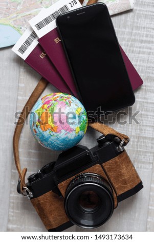 travel and vacation concept - close up of passports, tickets, map, smart phone and vintage camera on wooden table
