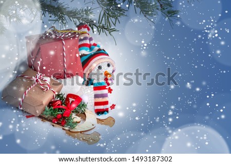 Christmas composition under the Christmas tree - a snowman, boxes with gifts on a sled and other decorations, place for text, copy space