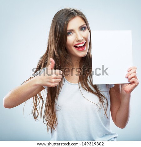 Teenager girl hold white blank paper. Thumb up.Young smiling woman show blank card. Girl portrait isolated on white background.