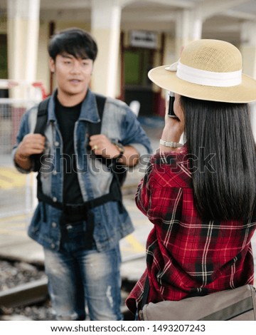 Couple of travel photographer enjoys taking photo during their trip at railway station. Asian  travelers with camera having fun making pictures while waiting for train.