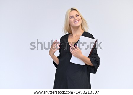Portrait of a cute girl, a young blonde woman with beautiful curly hair in a black dress on a white background with a folder in her hands. Beauty, brightness, smile, emotions.