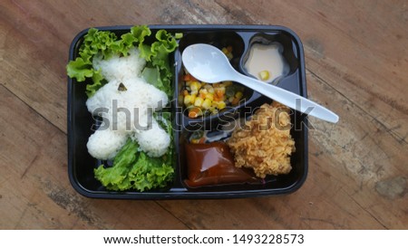 Panda-shaped rice with side dishes of crispy chicken and pickles.