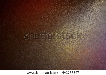 the texture of artificial leather is black with dramatic highlights of pink and green shades background image, close-up photo