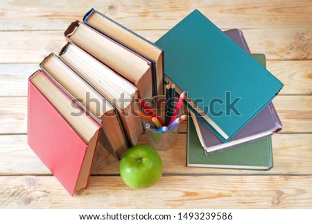 books pile, apple, pencils on wooden background, back to school concept, teacher's day concept, view of top