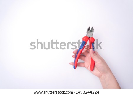 Fashion woman's hand with a gentle manicure holds a tool. Safe work, place for an inscription. View from above. White background, contrasting shadow. Cut.