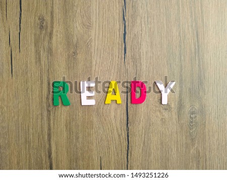 Ready written with colorful letters on wooden background