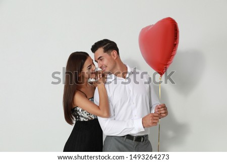 Beautiful couple with heart shaped balloon on light background
