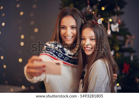 Mother and daughter celebrating Christmas at home and taking selfie