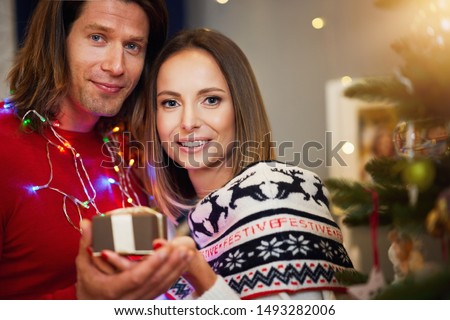 Beautiful adult couple with present over Christmas tree
