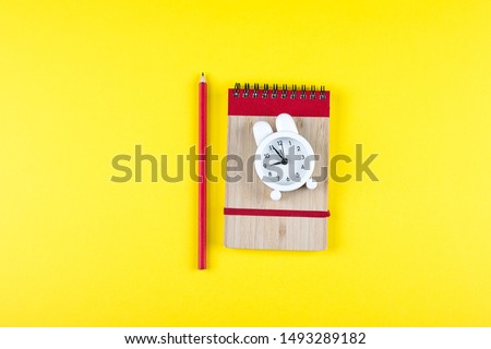 Back to school concept. Notepad, pencil, alarm clock on grey concrete background. Flat lay, top view, copy space