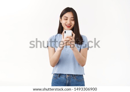 Excited carefree amused asian girl taking picture photographing girlfriend using smartphone camera hold phone look gadget screen amused smiling delighted social media blogger capture moment