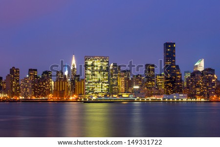 the buildings of manhattan at night in front of east river