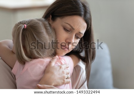 Attractive sad woman embraces little frustrated girl rear view, daughter snuggle to mother seeking for support and protection, concept of empathy and consoling or people make peace after scold concept Royalty-Free Stock Photo #1493322494