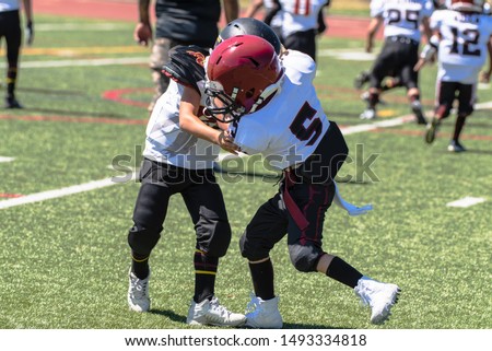 Opposing youth football players locked in each others grasp as they wrestle for dominant position. Royalty-Free Stock Photo #1493334818