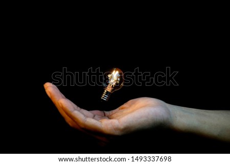 small vintage lightbulb on hand and black background,abstract  picture of energy magic concept  and idea thinking                     