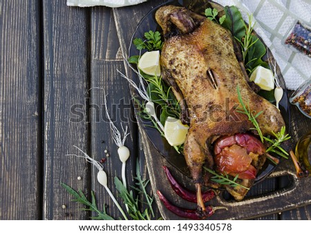 Tasty duck baked with apples, lemon and rosemary on a dark wooden table. Top view. Flat lay. Banner.