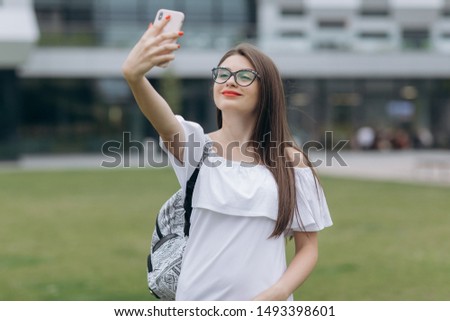 Woman wearing eyeglasses take a selfie. Beautiful young happy excited business woman posing walking outdoors near business center wearing eyeglasses take selfie by camera