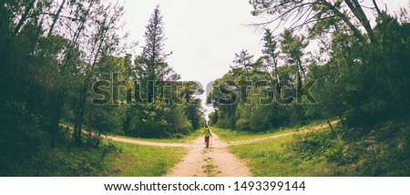 A woman stands at the crossroads of two forest roads. The girl at the crossroads. The choice of the path. Woman lost in the woods. The choice of ways to achieve the goal. Royalty-Free Stock Photo #1493399144