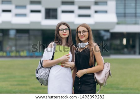 Two happy caucasian young women best friends having fun wearing trendy sunglasses, posing outdoor, looking at camera
