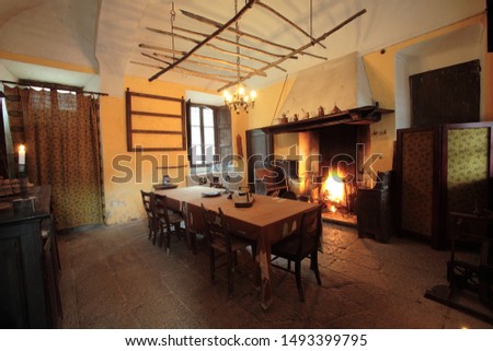Traditional kitchen of a countryhouse, with table in the middle and a fireplace in the background