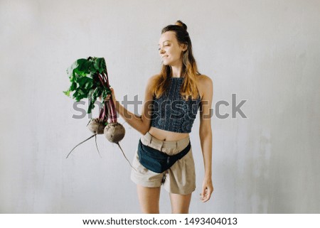 young pretty girl holding fresh organic beet on grey background