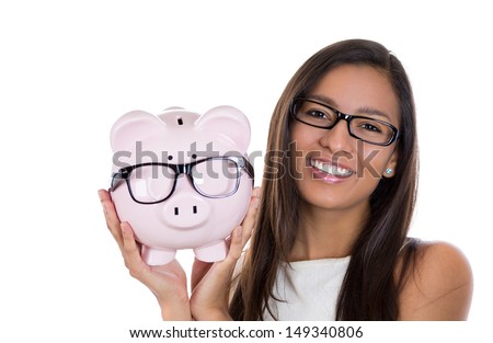 Closeup portrait of nerdy young woman holding piggy bank, both with big black glasses, isolated on white background. Positive emotion facial expression feelings. Smart wise financial decision savings