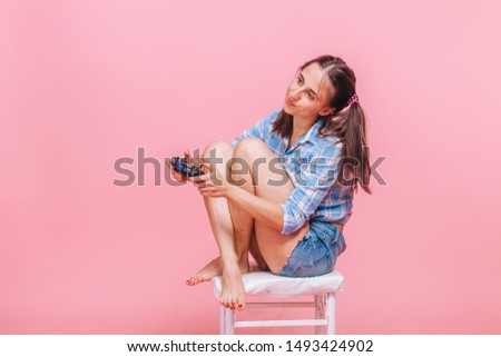 Girl with playing computer games with joystick on pink background