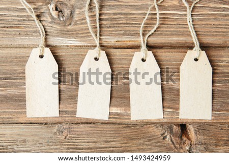 set of four tags hanging on rope on wooden background Four paper blank tags with rope on wooden background.