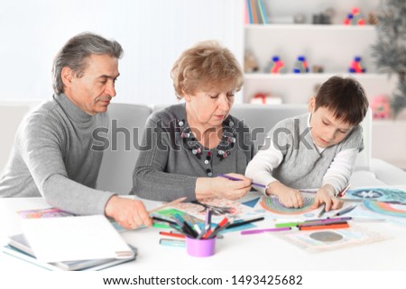 Little boy painting with grandpa and grandma. concept of education