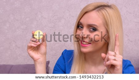 golden bitcoin in the hand of a beautiful blonde girl in blue dress