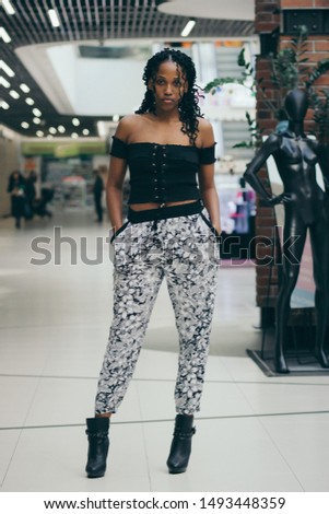 Young dark-skinned woman dressed in casual clothes in the mall, blurred background