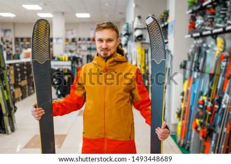 Man at the showcase holding downhill ski in hands
