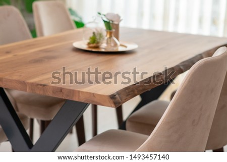 Corner of modern dining room with white walls, wooden floor, arched window and long wooden table with round chairs 