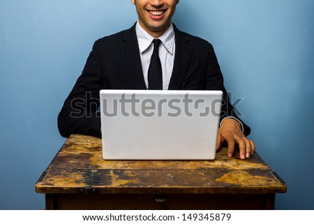 Happy businessman with laptop at old table