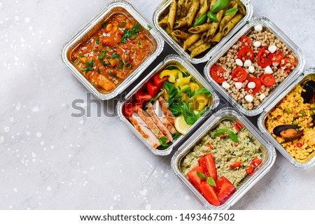 Food delivery.Different aluminium lunch box with healthy natural food pasta pesto, spelt, paella, quinoa, chicken salad, curry.  airlines food. airline meals and snacks . takeaway  Royalty-Free Stock Photo #1493467502