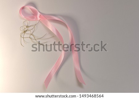 A pink ribbon in the hands of a flying pair of wire hearted little men.