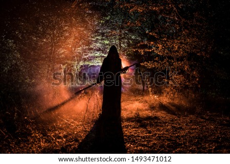Death with a scythe in the dark misty forest. Woman horror ghost holding reaper in forest, halloween concept