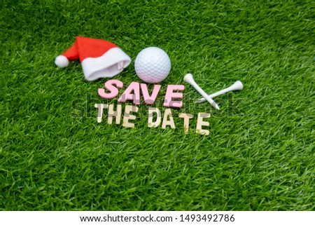 Golf Christmas save the date Christmas for golfer with Santa hat and golf ball tee on green grass.