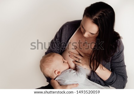 Mother breast feeding her 6-12 month old baby son on white background