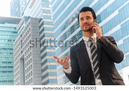 Smart caucasian businessman talking on his smartphone with background of the glass building  in business downtown center